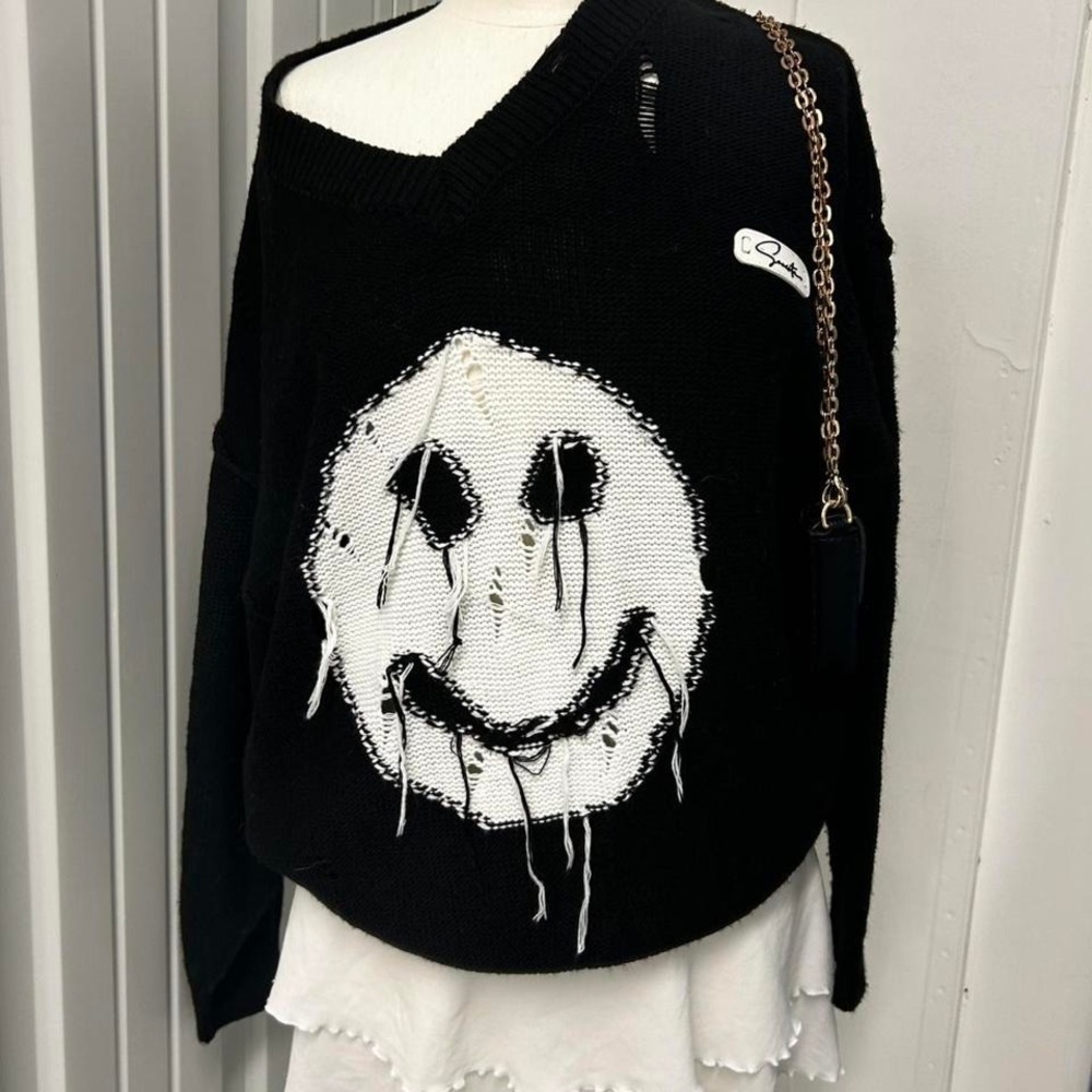 Black distressed knit sweater with a creepy smiley face graphic